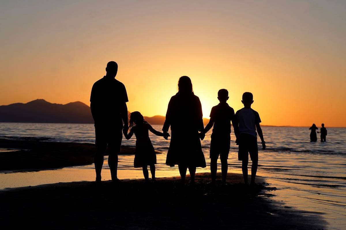 Visitors hold hands as they gather at the receding edge of the Great Salt Lake to watch the sun ...
