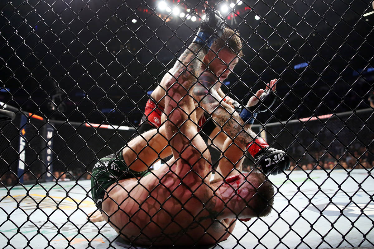 Dustin Poirier, top, lands a pinch against Conor McGregor in the first round of a lightweight b ...