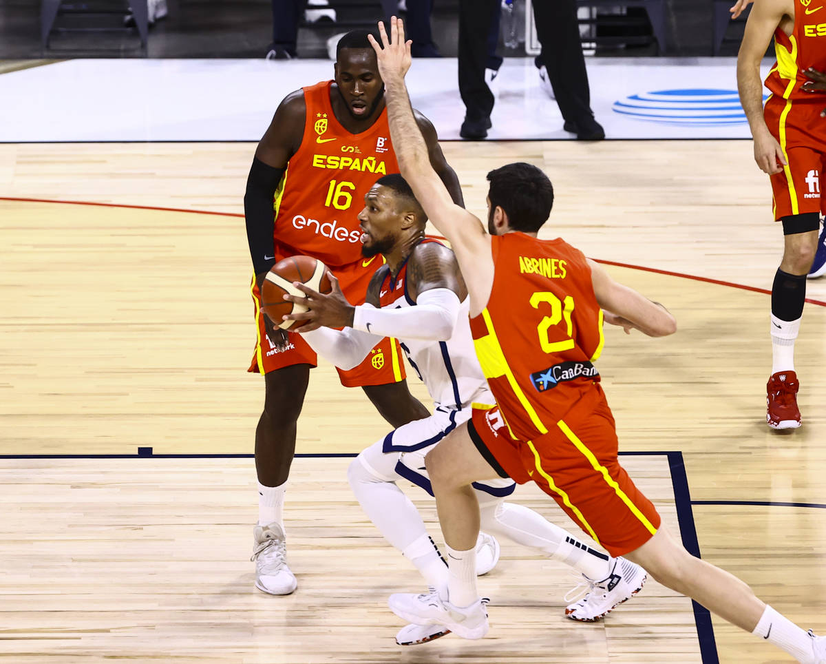 United States guard Damian Lillard, center, drives the ball under pressure from Spain forward U ...