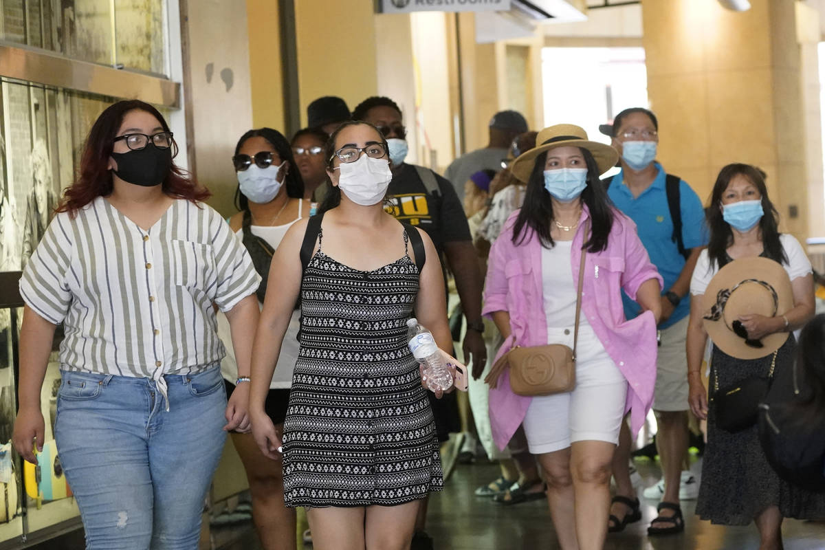 In this July 1, 2021, file photo visitors wear masks as they walk in a shopping district in the ...