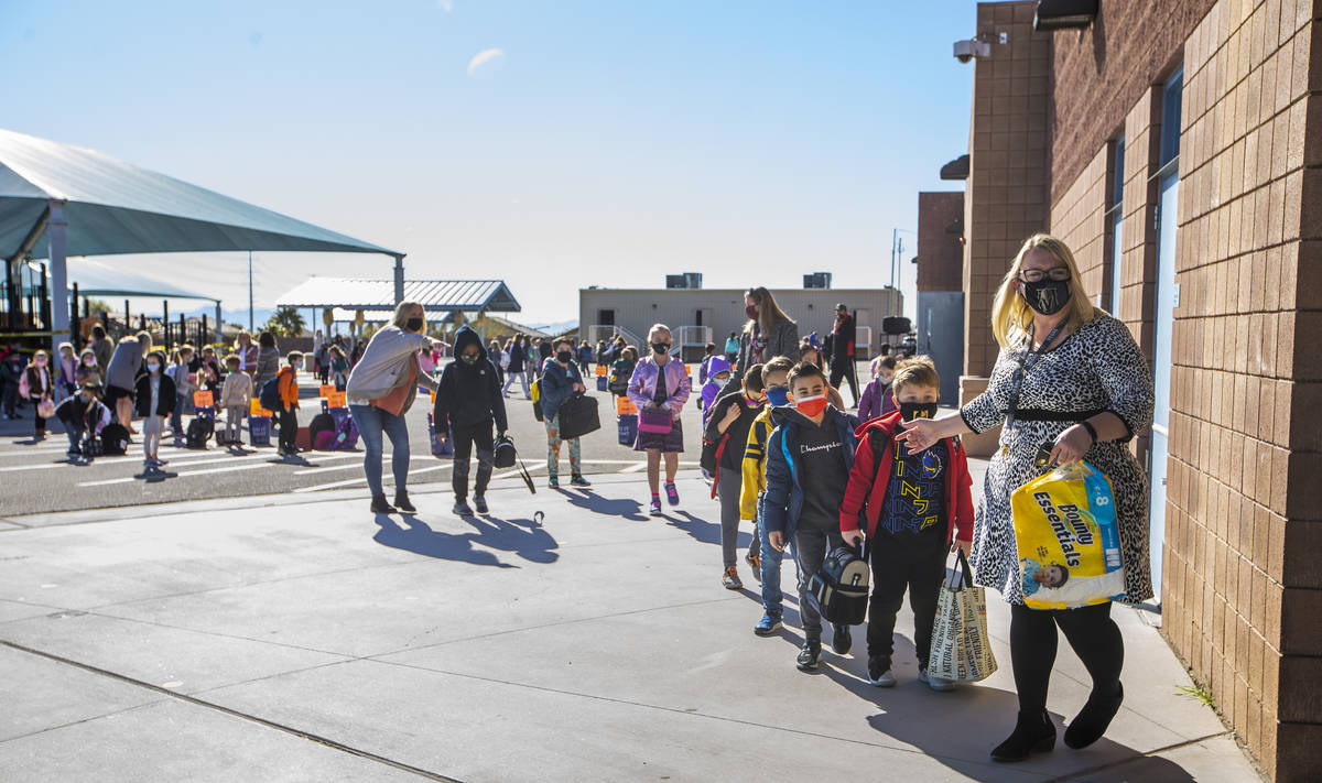 Teachers and other staff members lead students inside from the playground at Goolsby Elementary ...