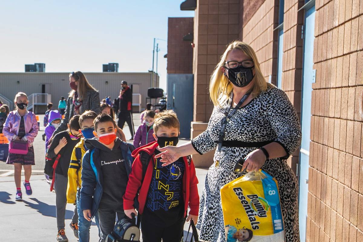 Teachers and other staff members lead students inside from the playground at Goolsby Elementary ...