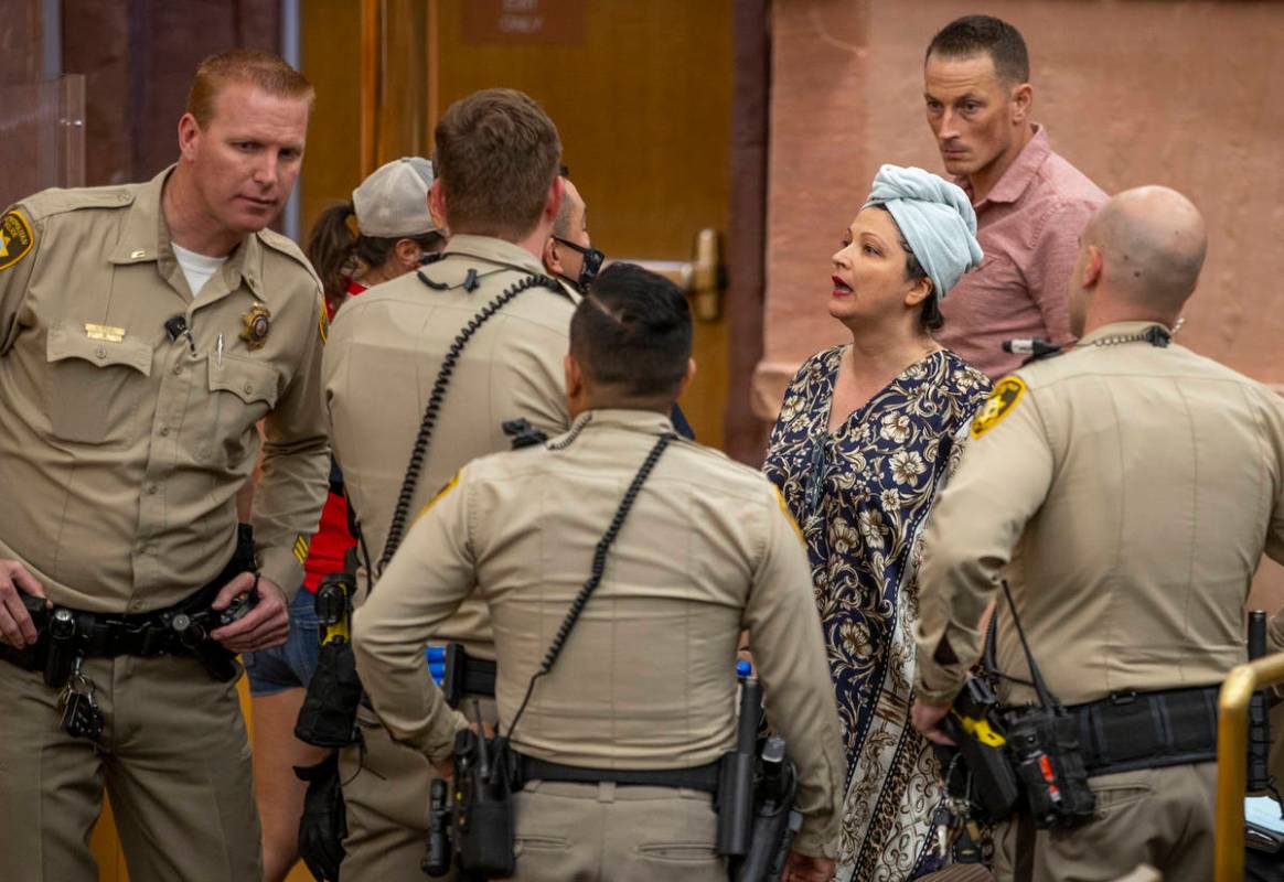 Officers speak with Katrin Ivanoff during the Clark County Commission meeting for public outbur ...