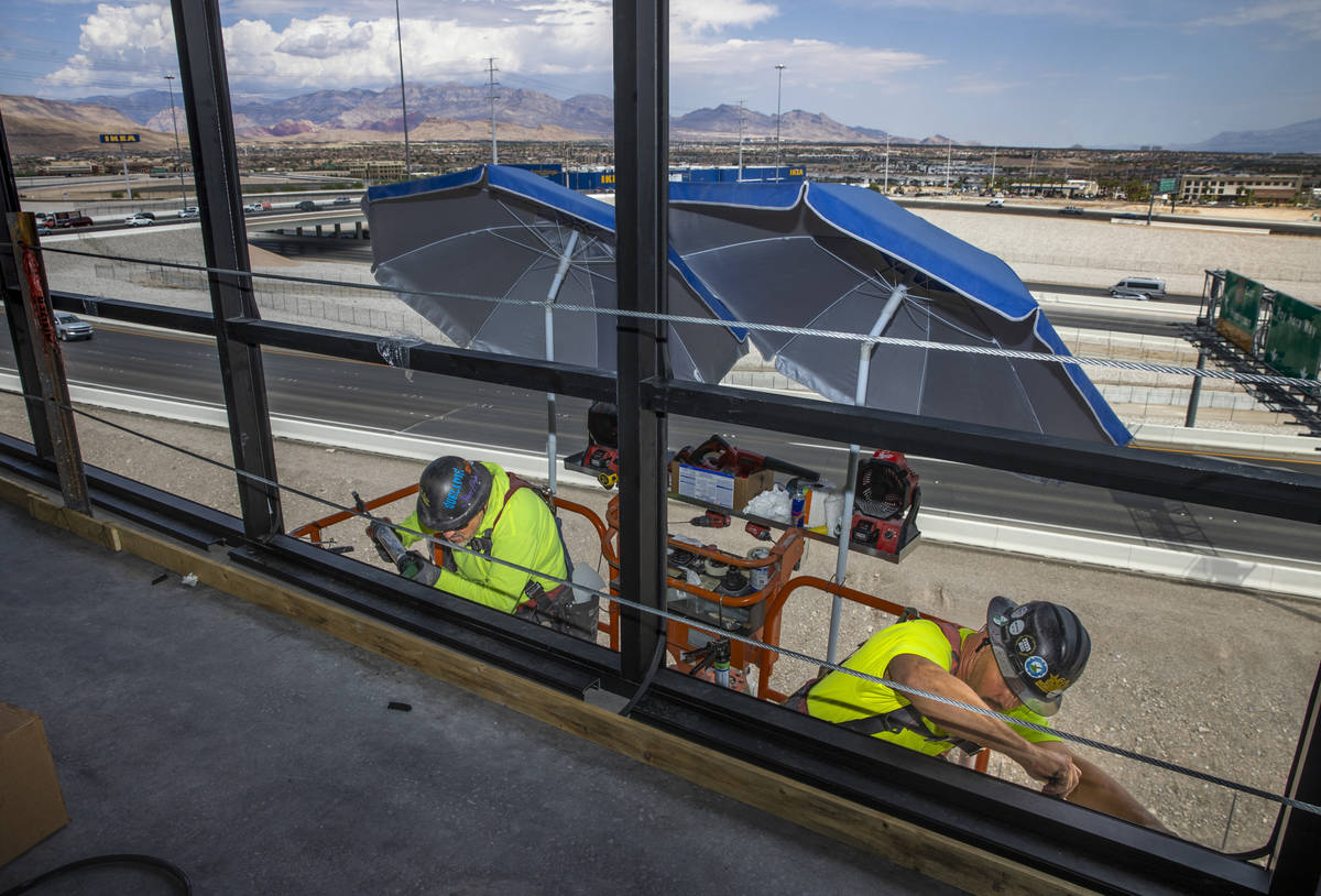 Eric Oudeman, left, and Tacoma McCormick of Quantum Glass and Mirror work the exterior atop Off ...