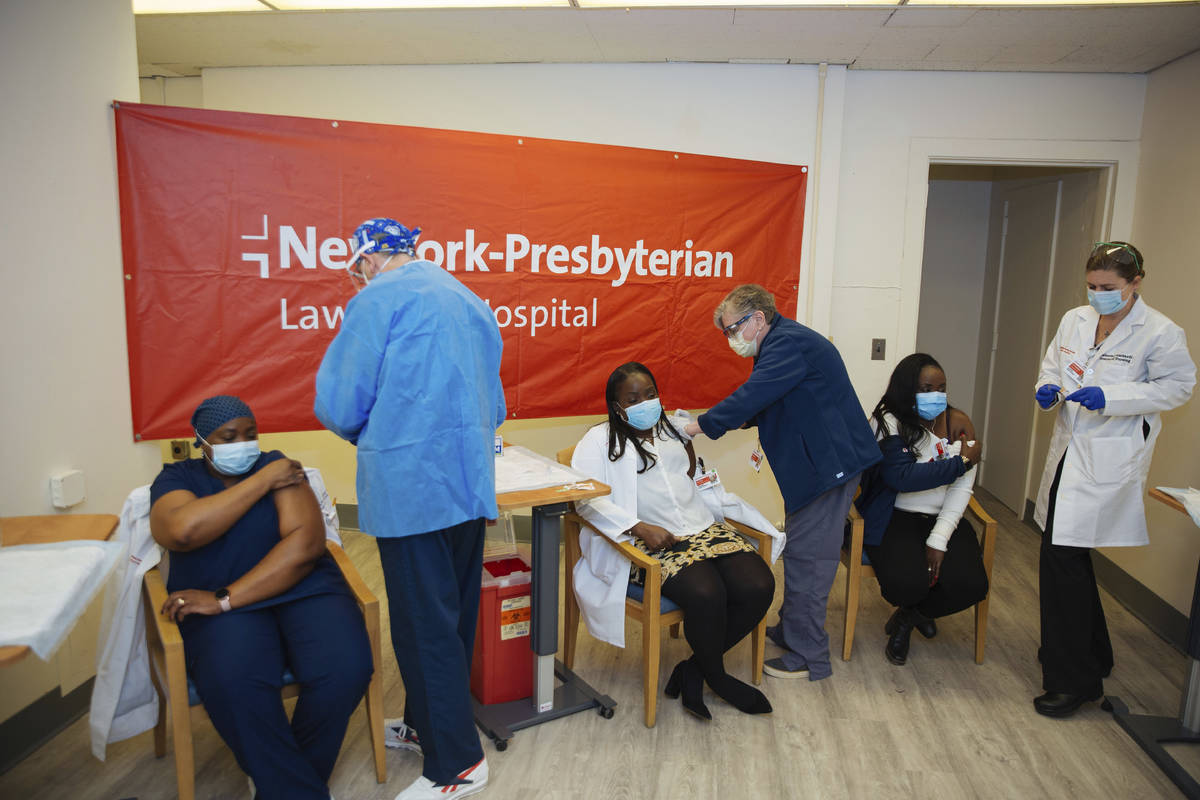 FILE - In this Friday, Jan. 8, 2021, file photo doctors inject sisters Claudia Scott-Mighty, le ...