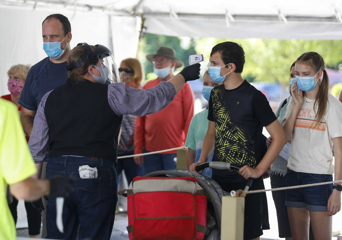 FILE - In this June 13, 2021, file photo, a Silver Dollar City employee takes the temperature o ...