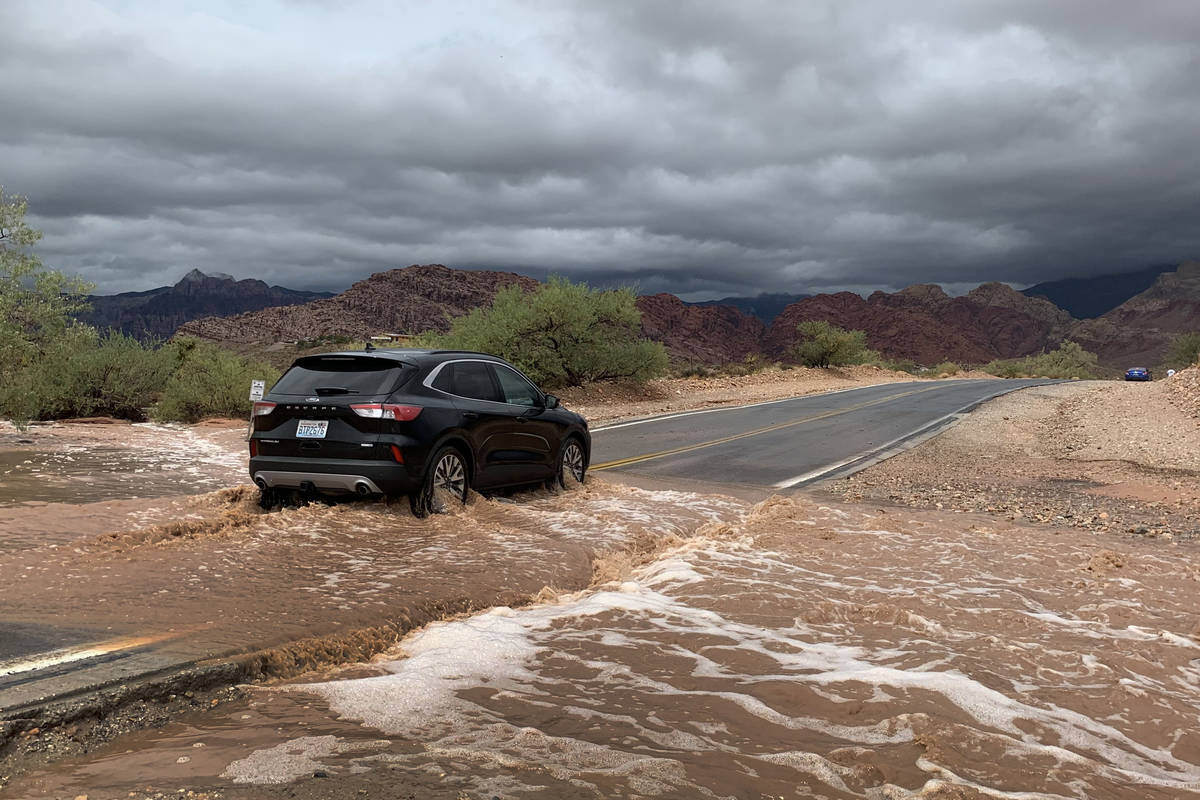 A vehicle drives through a flooded section of Calico Basin Road near Red Rock Canyon National C ...