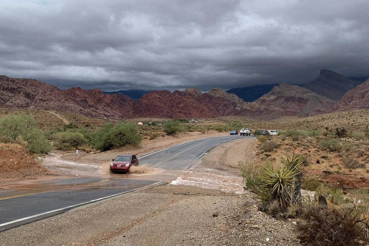 A vehicle drives through a flooded section of Calico Basin Road near Red Rock Canyon National C ...