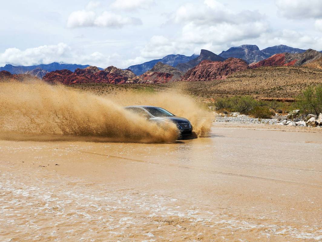 A car drives over a flooded portion of Blue Diamond Road near Red Rock National Conservation Ar ...