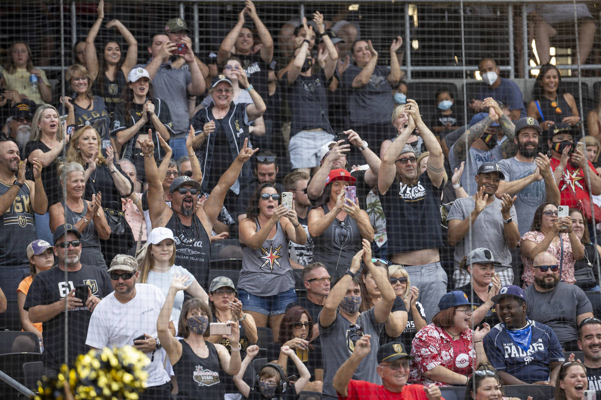 Fans cheers for the players during a charity softball game involving teammates from the Vegas G ...