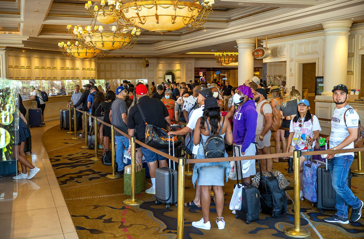 People stand in line to check in at Treasure Island, a large percentage not wearing masks anymo ...