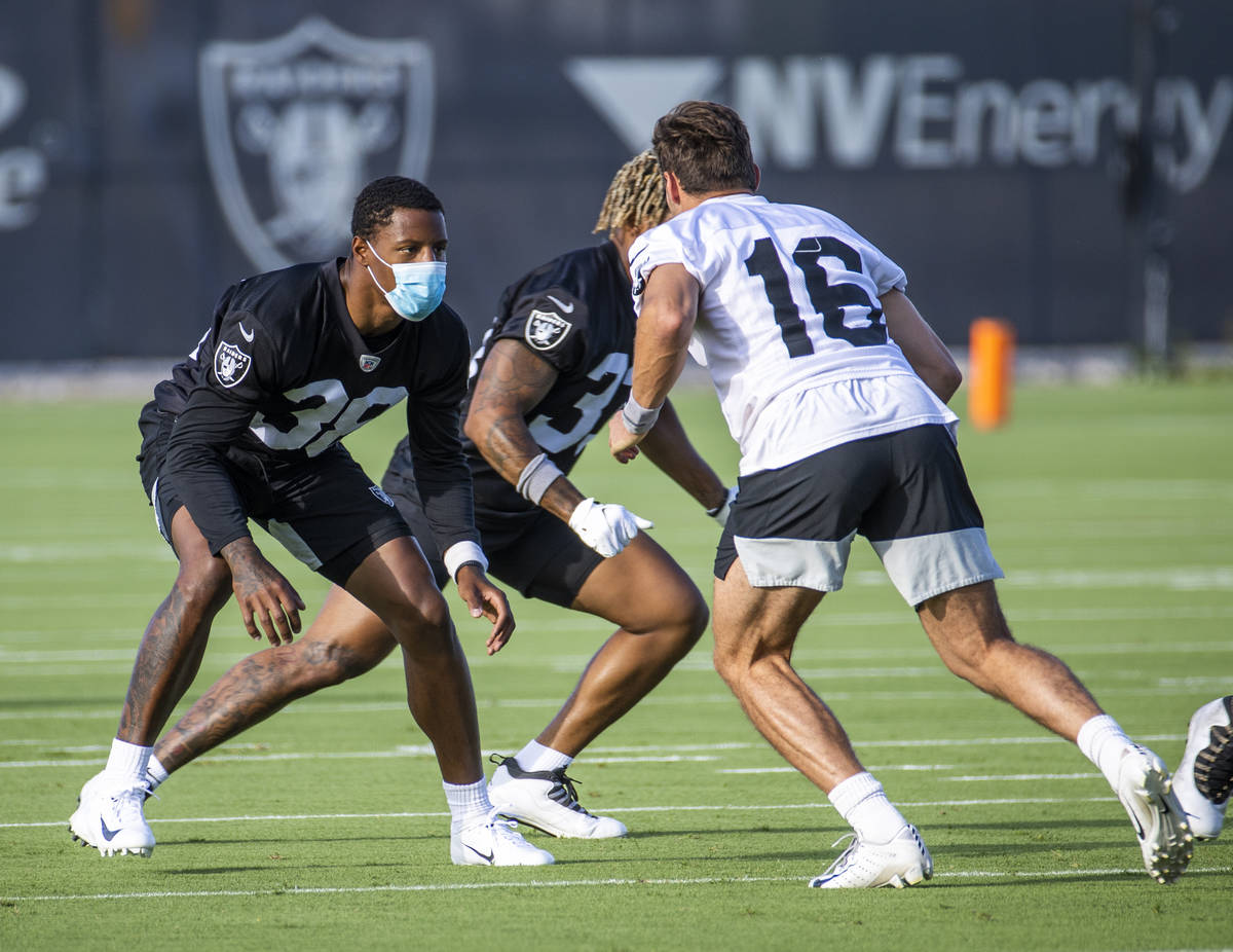 Raiders cornerback Rasul Douglas (38, left) wears a mask while defending against teammate wide ...