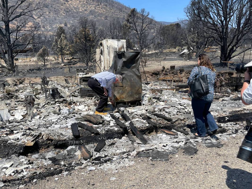 Gov. Steve Sisolak bends down to retrieve an unbroken mug from a rubble of a home destroyed in ...