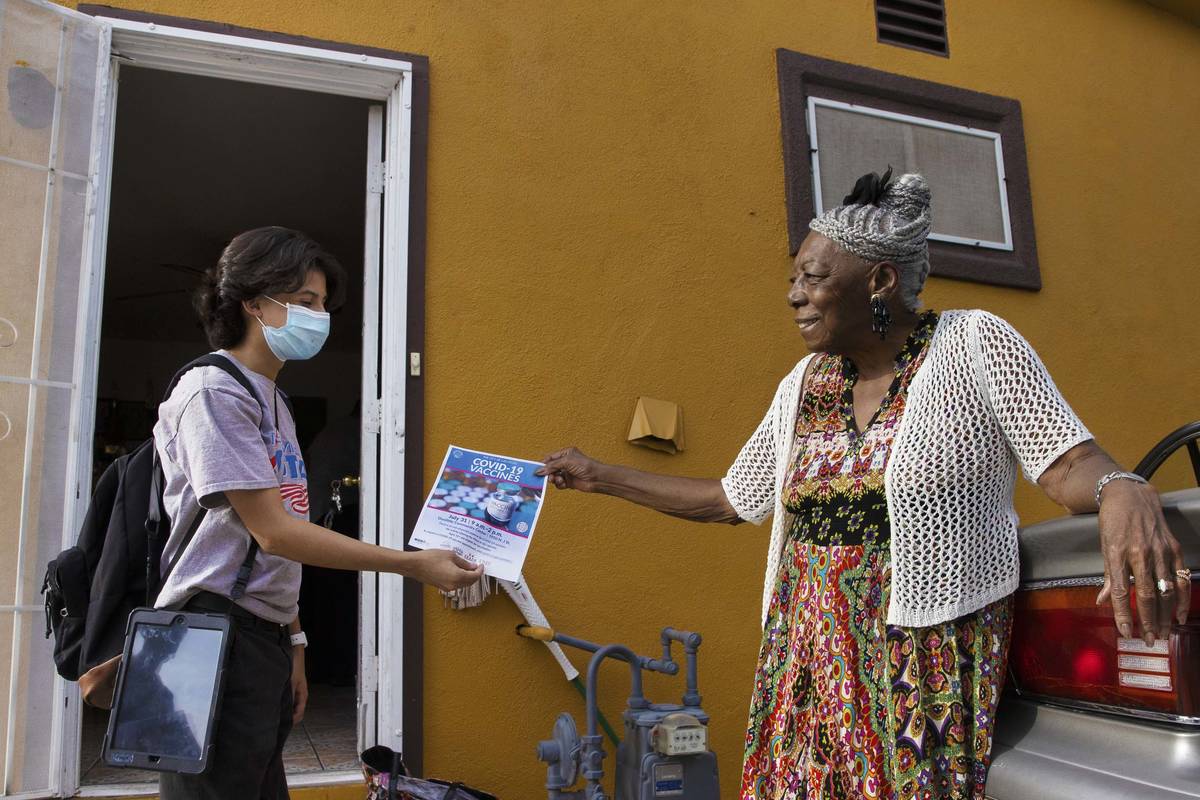 Jacinto Alfaro, left, a volunteer with the nonprofit Mi Familia Vota, hands a COVID-19 vaccine ...