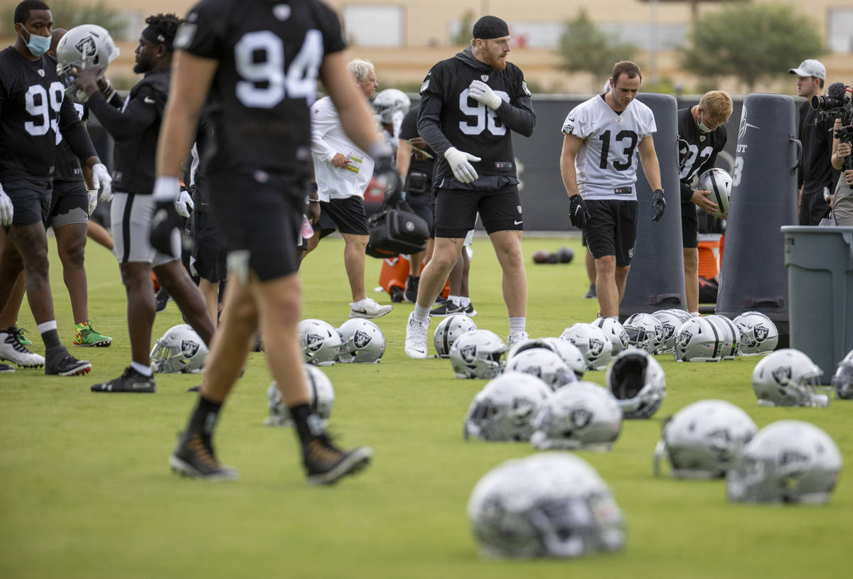 Raiders defensive end Maxx Crosby (98) and teammates head to their helmets during training camp ...