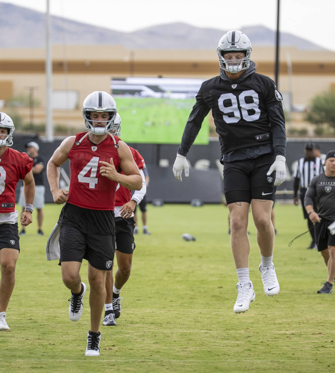 Raiders defensive end Maxx Crosby (98) leaps in the air as quarterback Derek Carr (4) runs alon ...