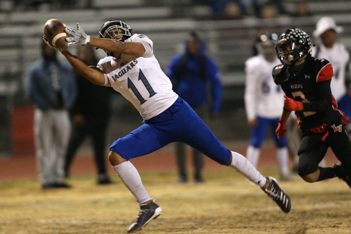 Desert Pines Jett Solomon (11) makes a catch under pressure from Las Vegas Lane Adaro (3) durin ...