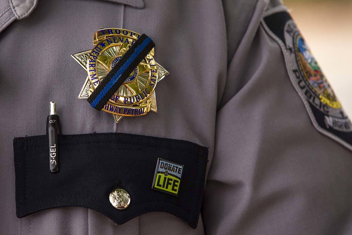 Nevada Highway Patrol Trooper Noah Villa wears a black band on his badge in remembrance of fell ...