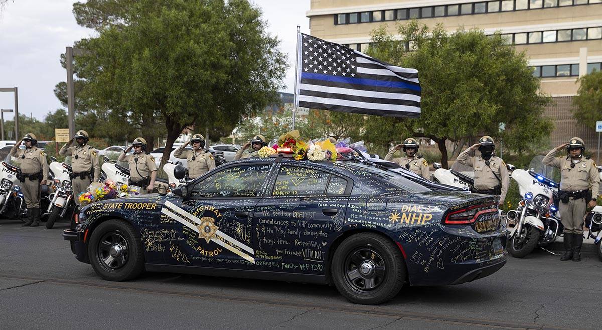 Las Vegas police officers salute to a procession moving the body of slain Nevada Highway Patrol ...
