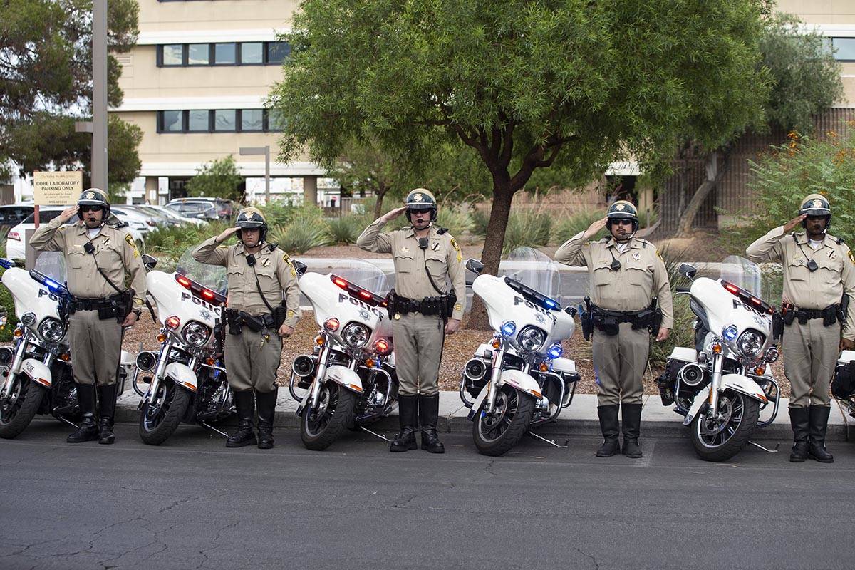 Las Vegas police officers salute to a procession moving the body of slain Nevada Highway Patrol ...