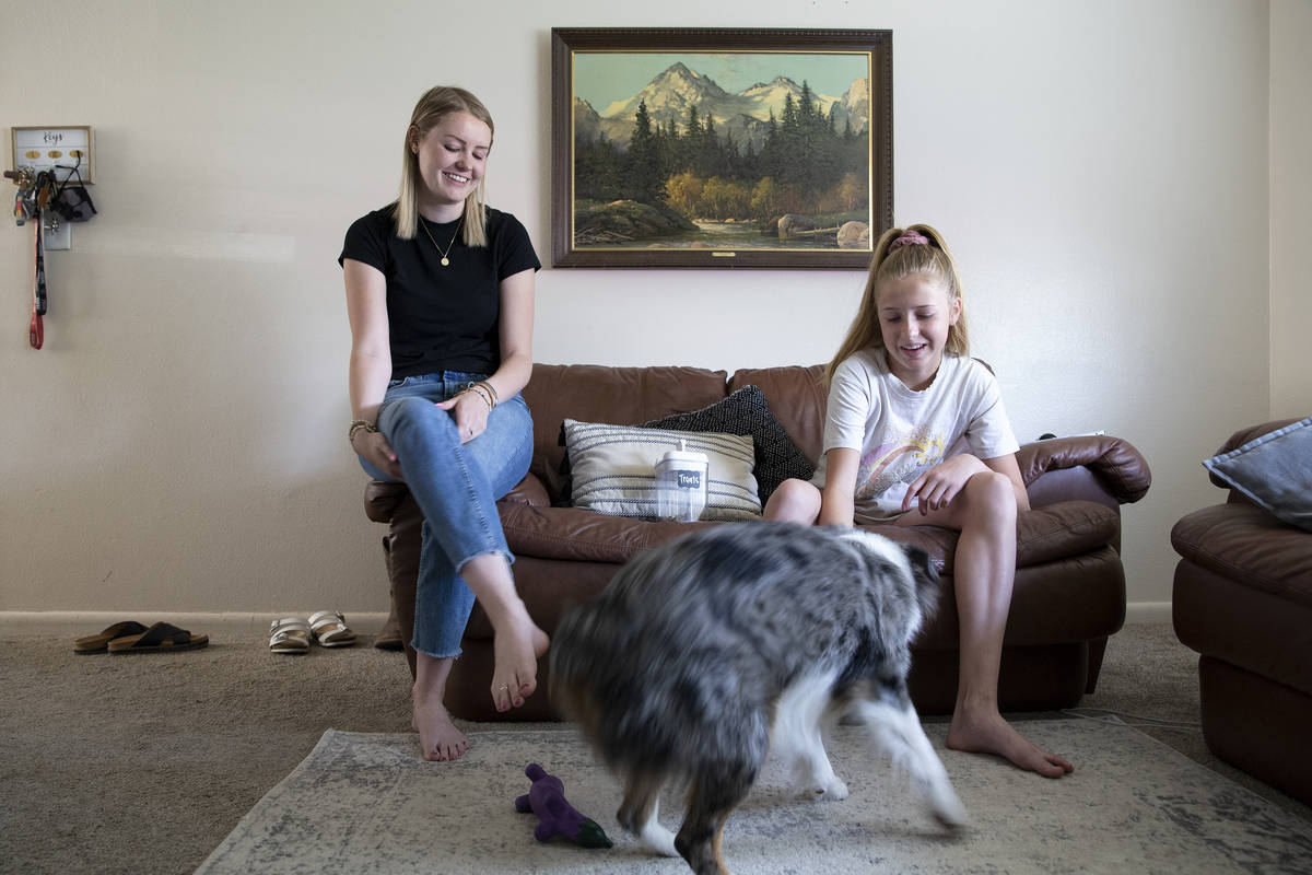 Kylee Tobler and her little sister, Anni, play with her dog, Benny, in the living room of her B ...