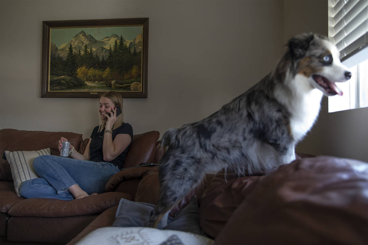 Kylee Tobler Fuqua speaks with her mom on the phone while her dog, Benny, looks out the window ...