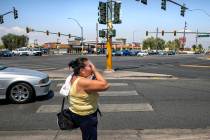 A woman wipes sweat from her face while walking at the intersection of North Eastern Avenue and ...