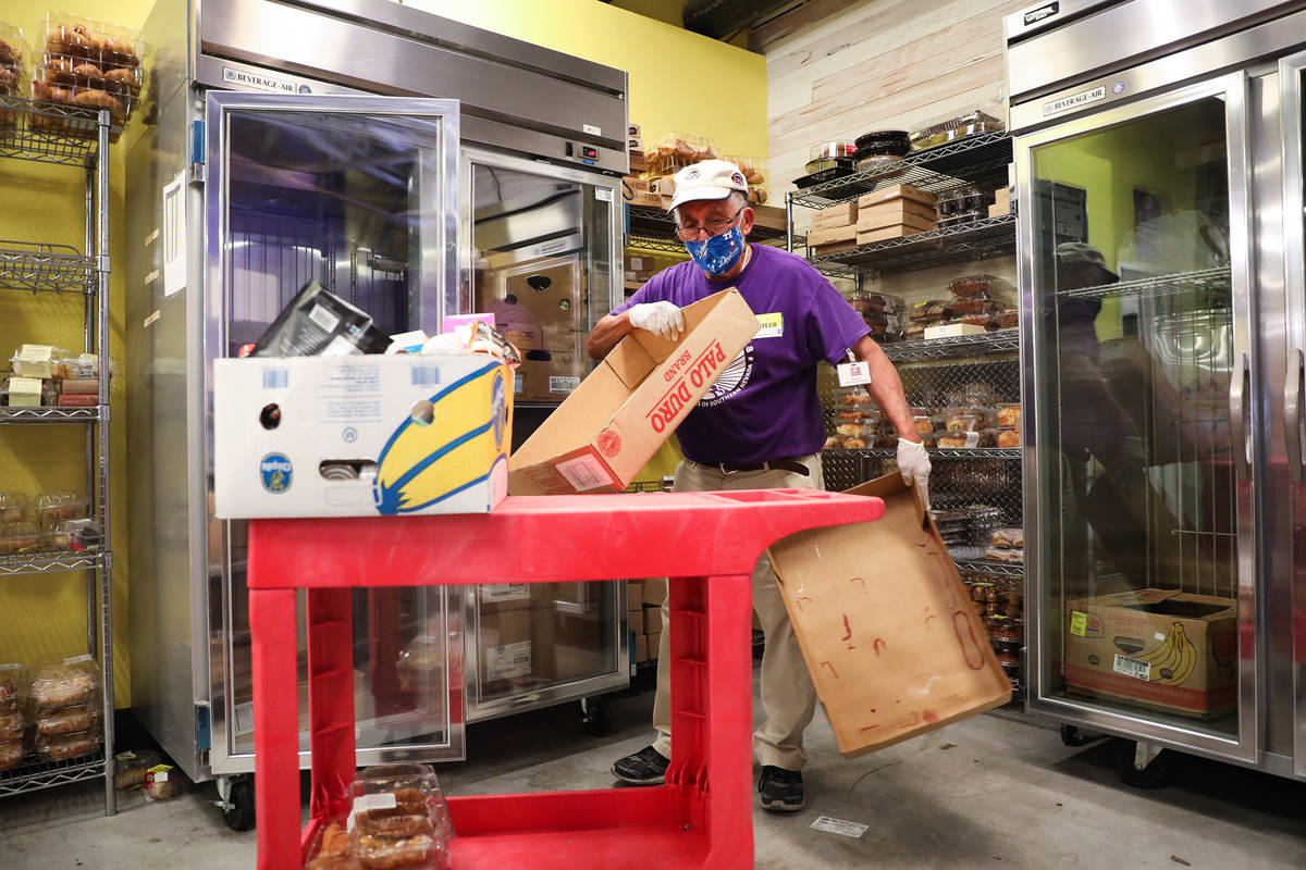 Volunteer Clarence Tabor folds up cardboard as he packs a box of food for pick up in the food p ...