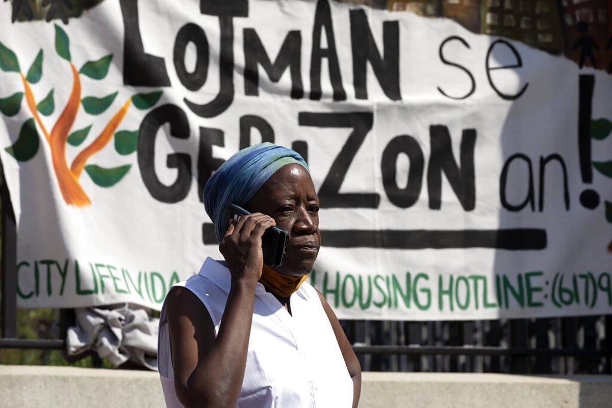 A woman speaks on the phone in front of a sign in Haitian Creole during a news conference held ...