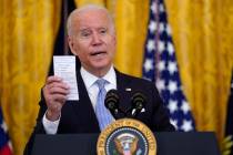 President Joe Biden holds a note card that has the number of COVID-19-related American deaths a ...