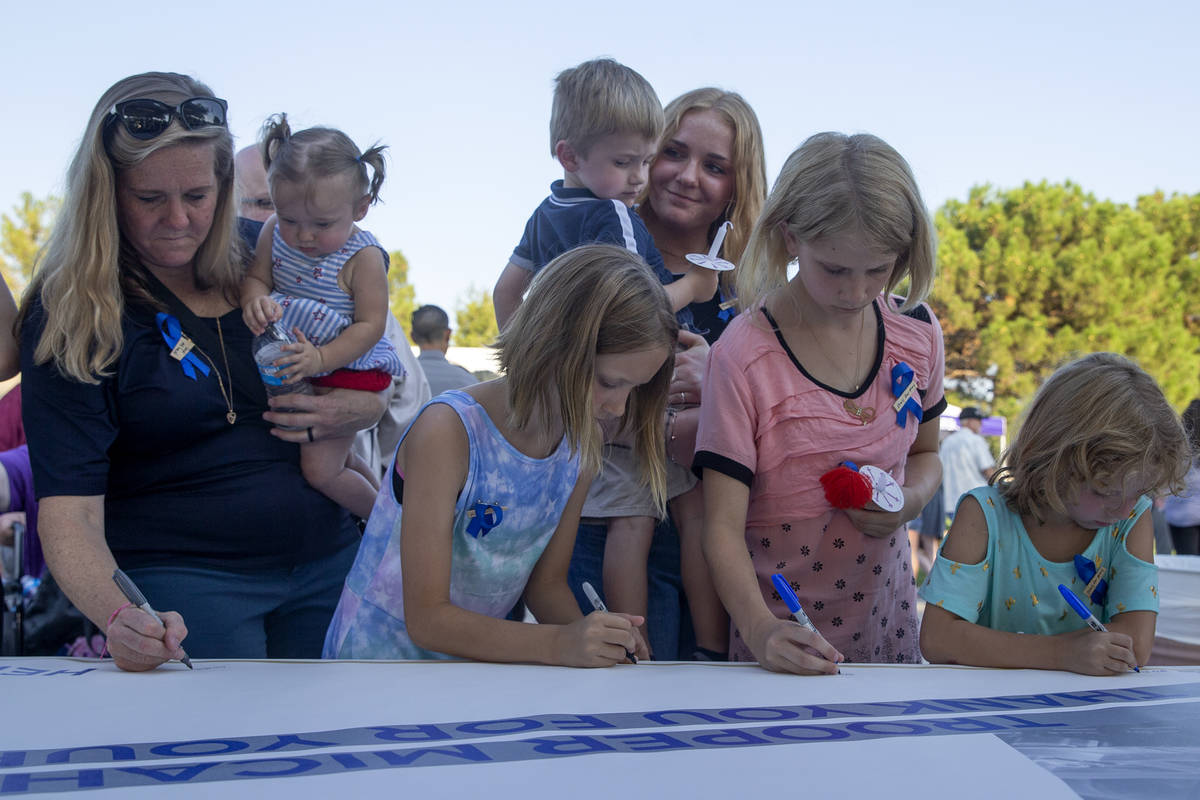 Family members hold Nevada Highway Patrol trooper Micah May's children Melody May, left, and Ra ...
