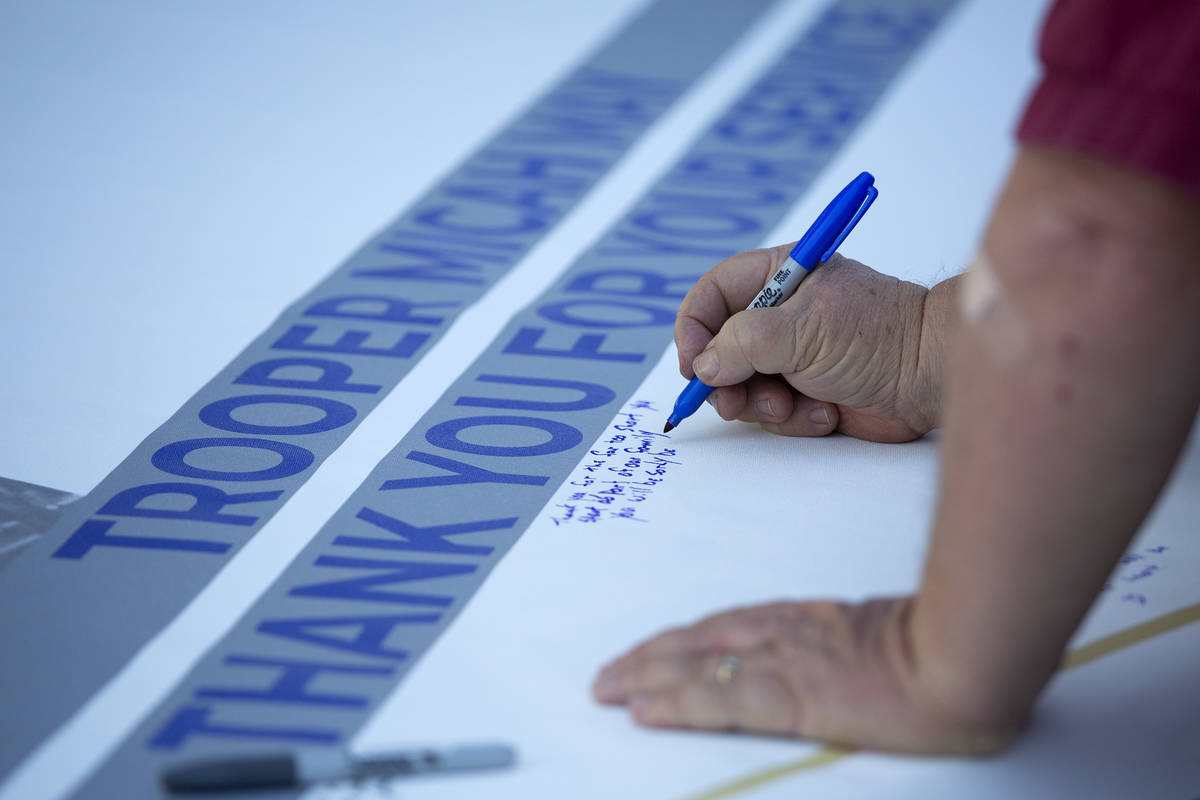 Family, friends and colleagues sign a banner for fallen Nevada Highway Patrol trooper Micah May ...