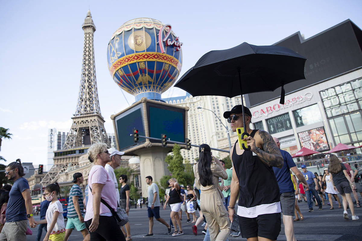 A visitor to the Las Vegas Strip uses an umbrella to shade himself from the sun on Wednesday, J ...