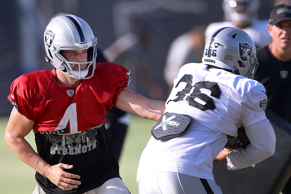 Las Vegas Raiders quarterback Derek Carr (4) hands off the ball to running back Trey Ragas (36) ...