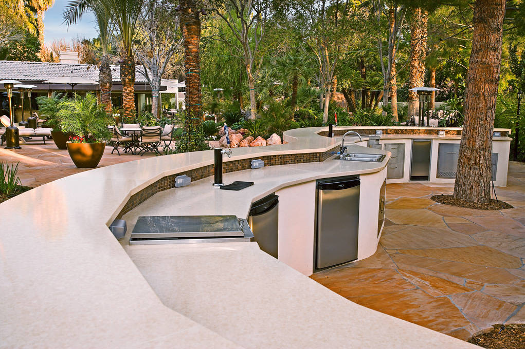 This outdoor kitchen features a 90-foot, S-shaped bar that wraps between two mature pine trees ...