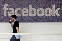 FILE - In this March 15, 2013, file photo, a Facebook employee walks past a sign at Facebook he ...