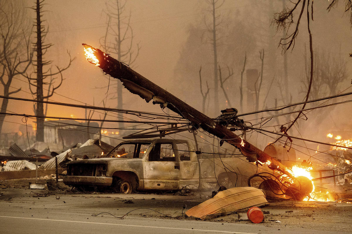 A utility pole burns as the Dixie Fire tears through the Greenville community of Plumas County, ...