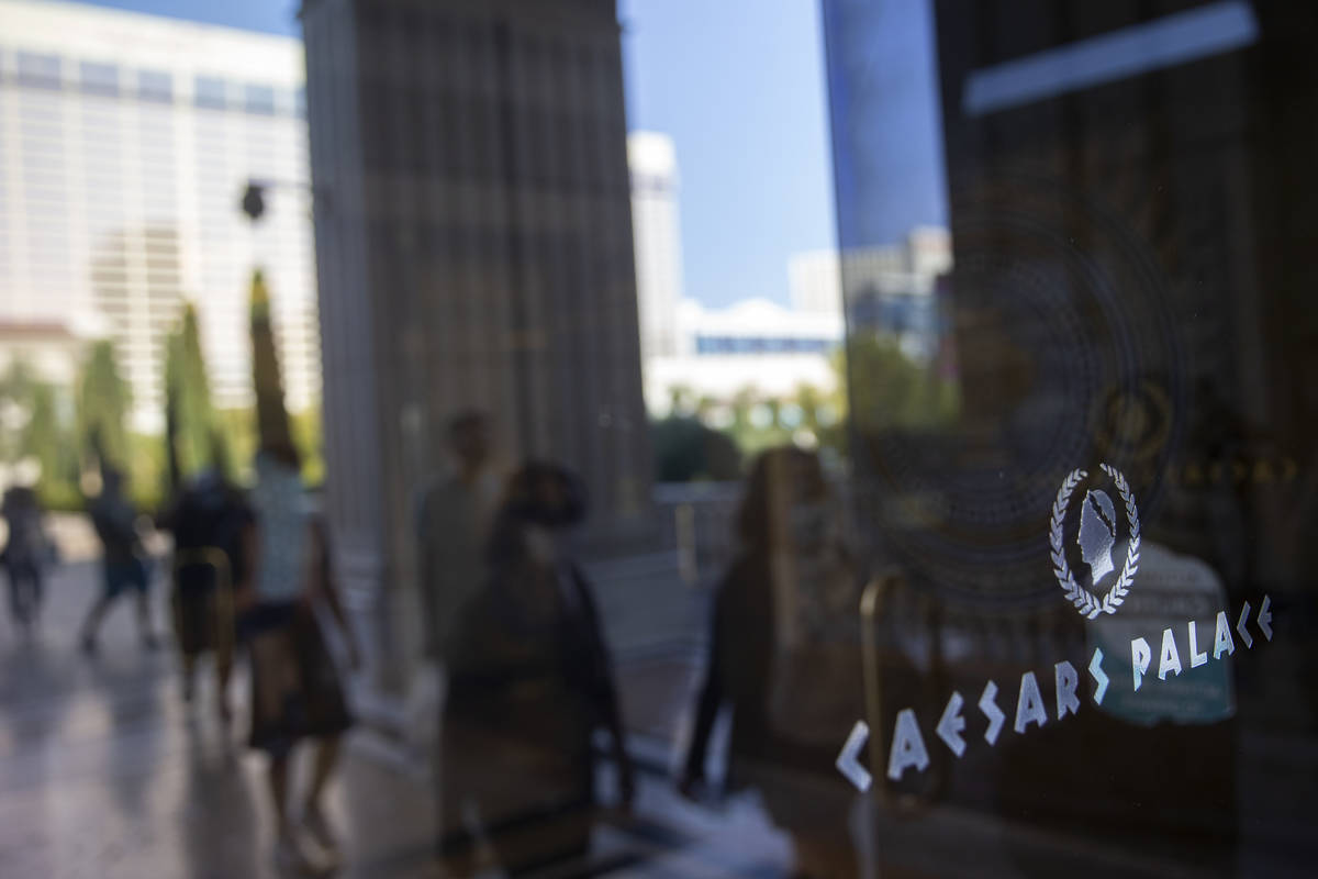 Visitors to the Las Vegas Strip are reflected in the door while entering Caesars Palace on Wedn ...