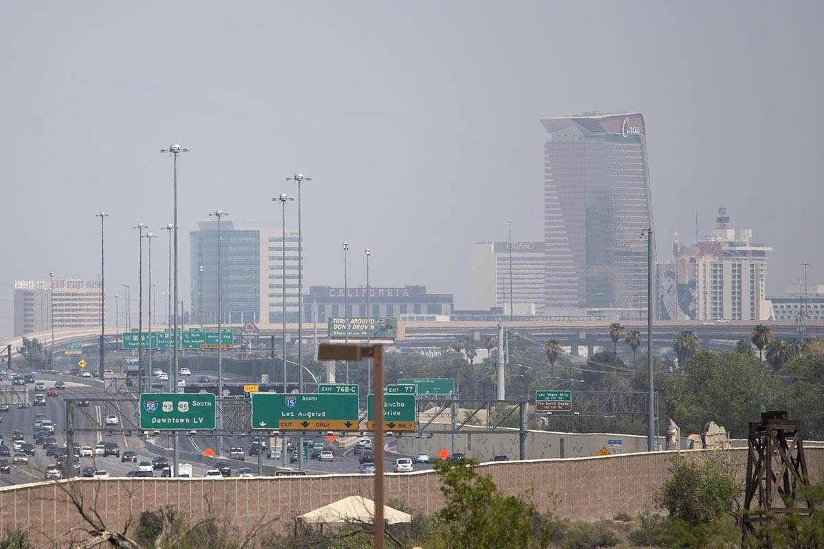 Traffic moves along US 95 and Interstate-15 while smoky skies cloud the downtown skyline on Sat ...
