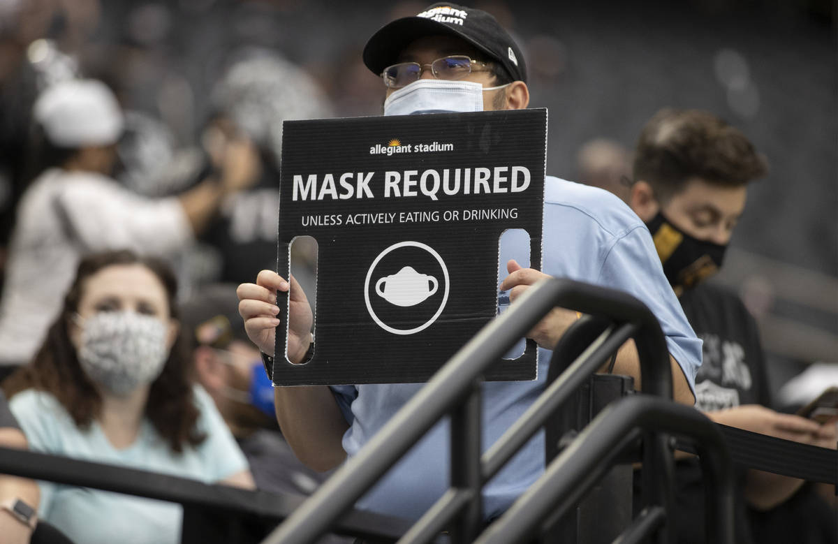 An usher hods a sign directing fans to wear masks during a special training camp practice for s ...
