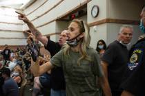 Protesters against a COVID-19 mandate gesture as they were escorted out of the Clark County Sch ...