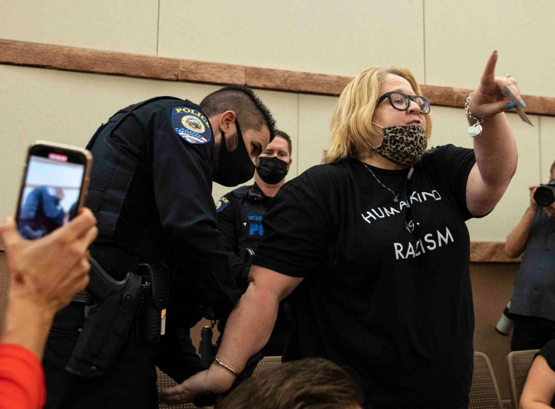 A protester, protesting against a COVID-19 mandate, reacts as she was arrested and escorted out ...