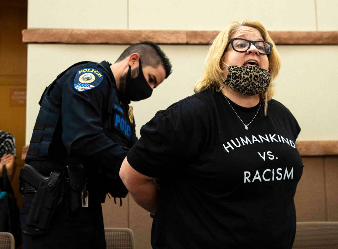 A protester, protesting against a COVID-19 mandate, reacts as she was arrested and escorted out ...