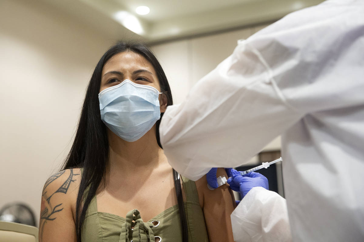 Vanessa Dizon, a cocktail server at Resorts World Las Vegas, grimaces while receiving a COVID-1 ...