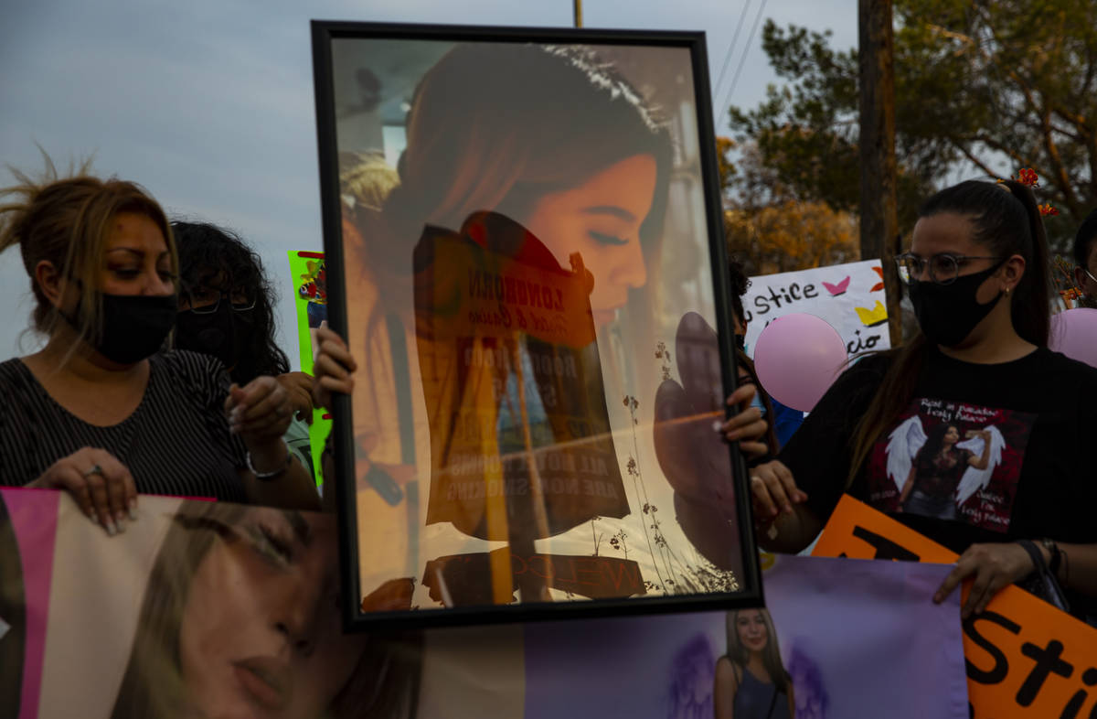 Family members and other people hold pictures of Lesly Palacio, who was found slain near Valley ...