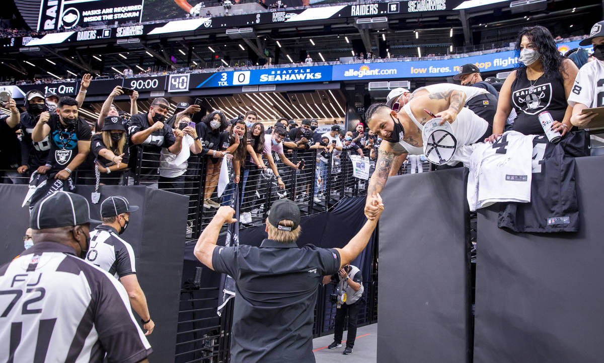 Raiders head coach Jon Gruden greets fans while leaving the field before the Raiders home openi ...