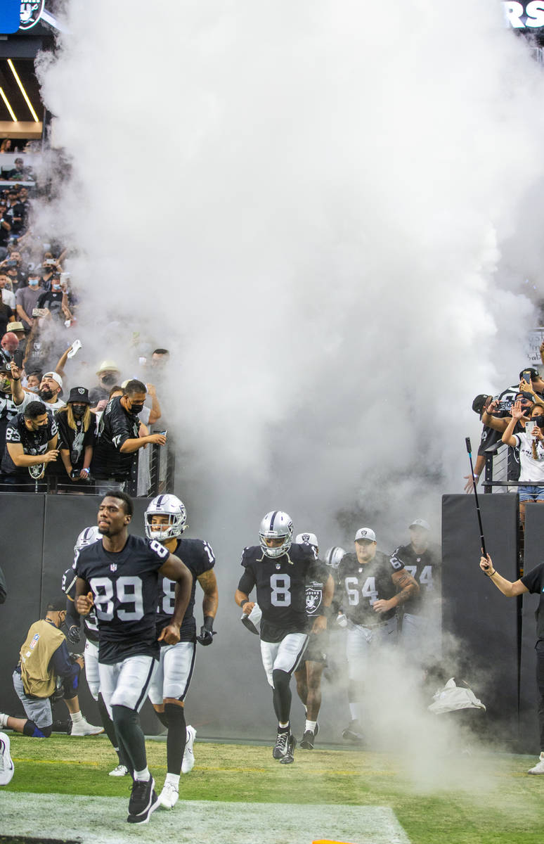 Players take the field running through smoke before the Raiders home opening pre-season NFL foo ...