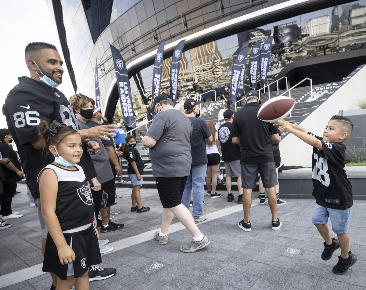 Raiders fan Eddie Valencia Jr., right, throws a pass to his dad Eddie Valencia outside Allegian ...