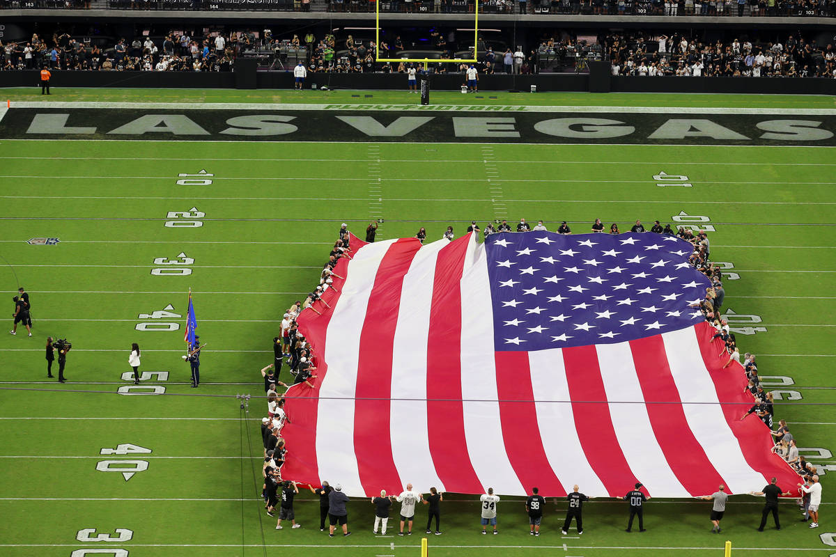 An America flag is displayed on the field during the singing of the national anthem by Marie Os ...