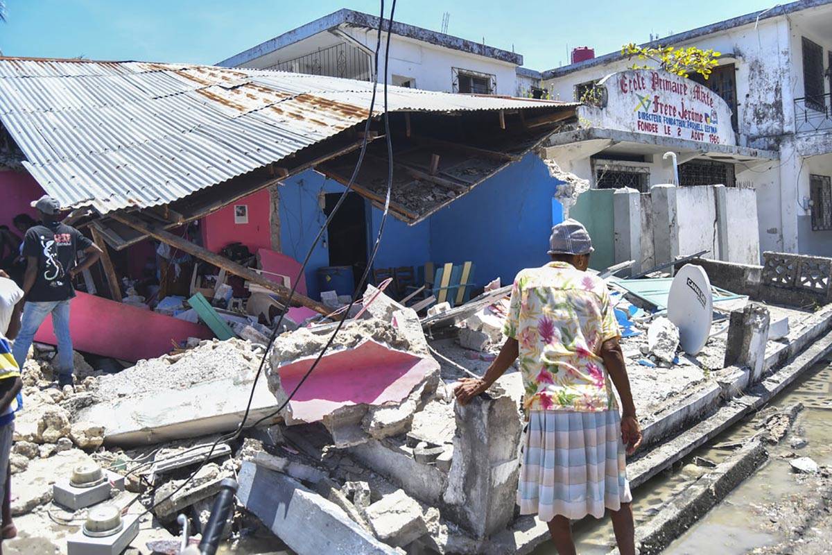 A woman stands in front of a destroyed home in the aftermath of an earthquake in Les Cayes, Hai ...